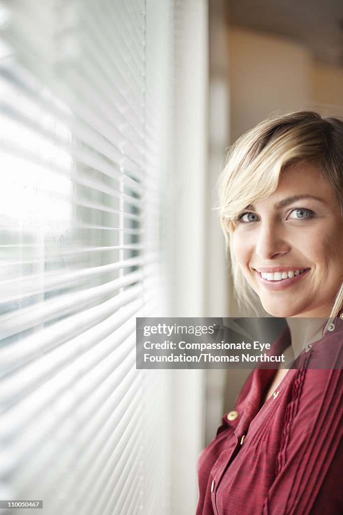 Portrait of smiling woman beside an office window