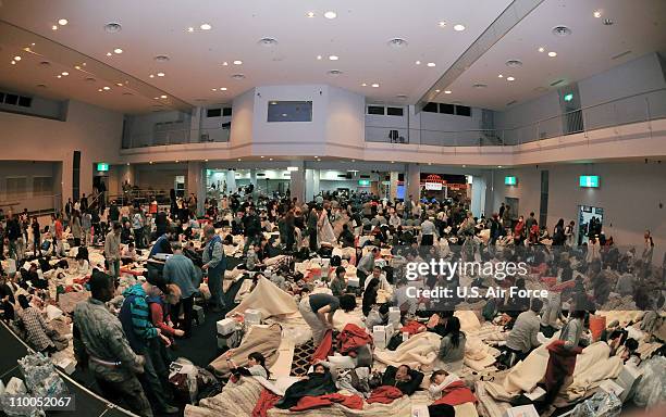 In this handout image provided by U.S. Air Force, American Red Cross volunteers provide blankets and pillows to passengers of a commercial airline...