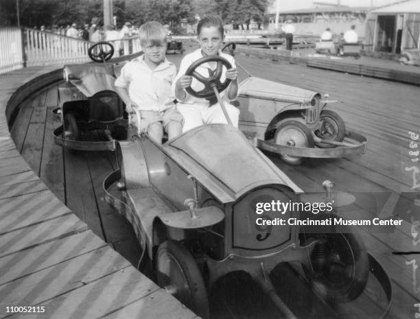 Portrait of two unidentified boys behind the wheel of a 'Custer Car' on a wood-floored track at the Coney Island amusement park, Cincinnati, Ohio,...