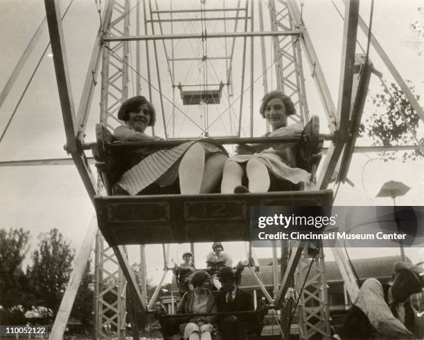 Low-angle portrait of a pair of young women as ride the Ferris wheel at the Coney Island amusement park, Cincinnati, Ohio, 1927.