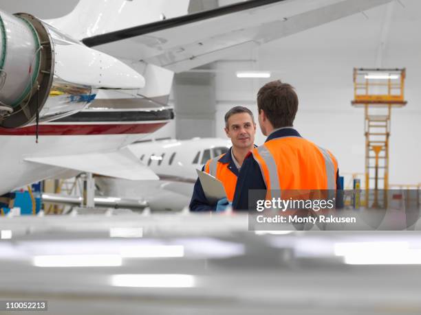 engineers in aircraft hangar with jets - flugzeug hangar stock-fotos und bilder