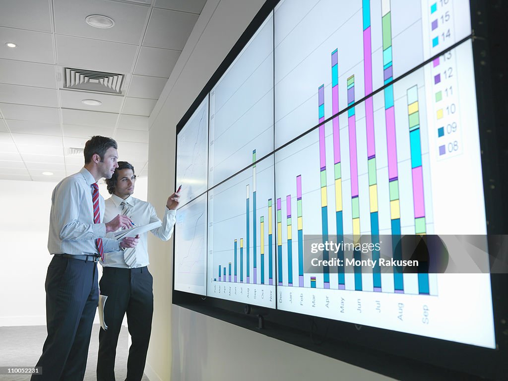 Businessmen with graphs on screen