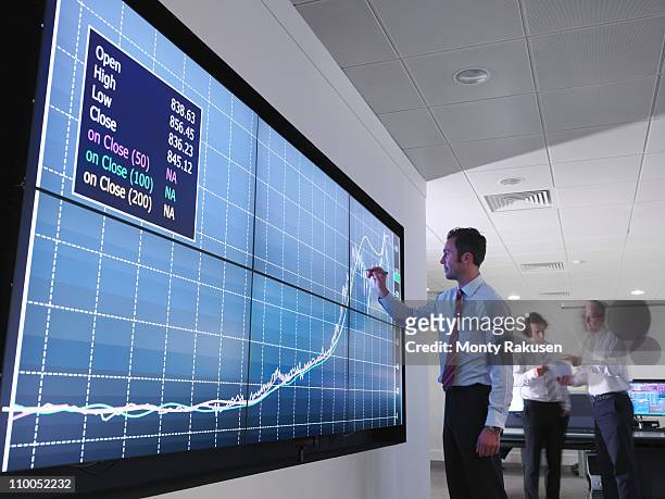 businessman using graphs on screen - forecasting stock photos et images de collection