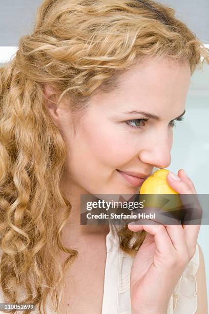 woman smelling on lemon - agrumi foto e immagini stock