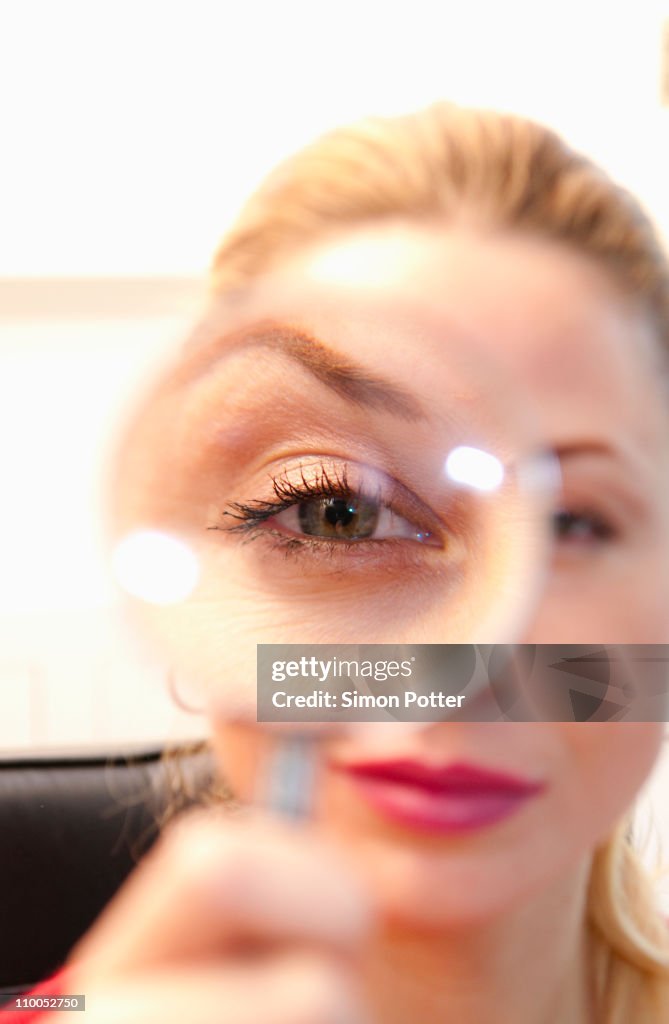 Woman looks thru magnifying glass