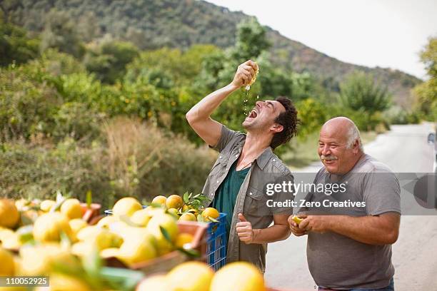männer squashing orange - greek food stock-fotos und bilder
