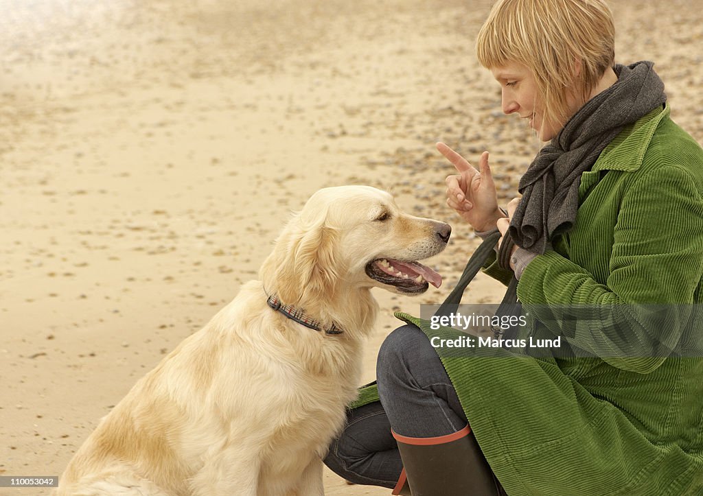 Woman training dog on beach Autumn Fall