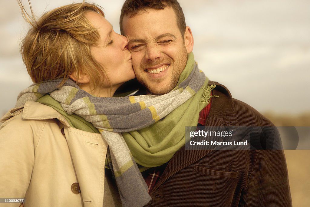 Woman kissing man on beach scarves mixed