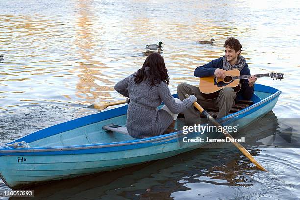 mann spielt gitarre in row boot - serenading stock-fotos und bilder