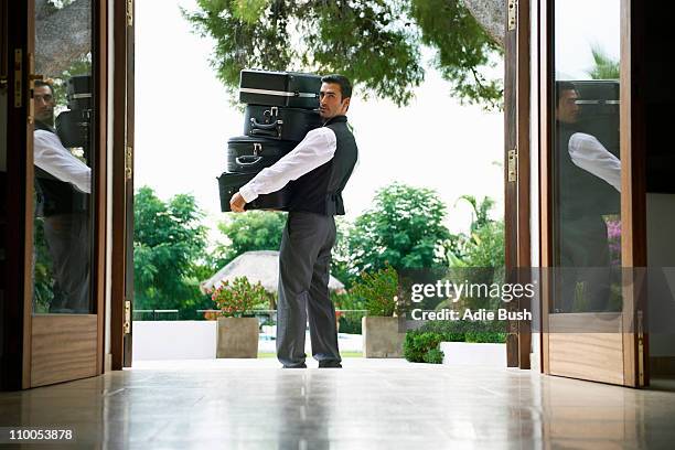 man carrying suitcases into hotel - bell boy stock pictures, royalty-free photos & images