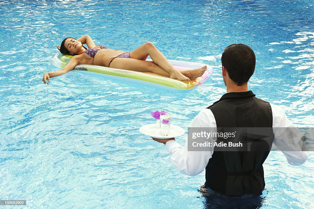 Waiter serving drinks to girl in a pool