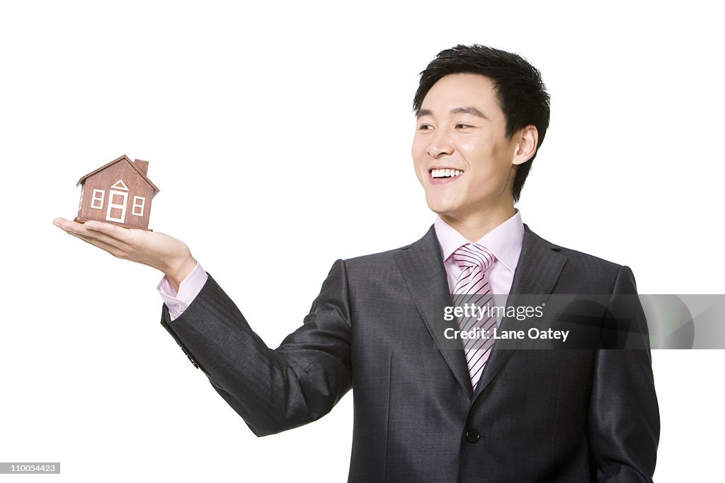 Businessman holding a small wooden model home