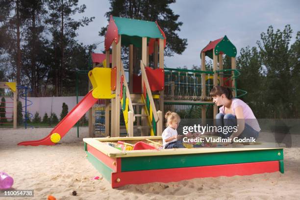 a mother and daughter playing in a sandbox - zandbak stockfoto's en -beelden