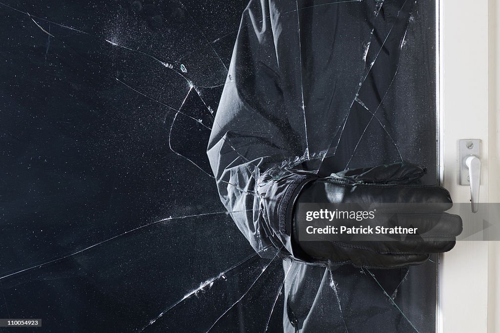 A criminal breaking into a window, focus on hand