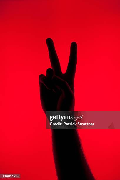 a silhouetted hand making a peace sign - victory sign man stock-fotos und bilder