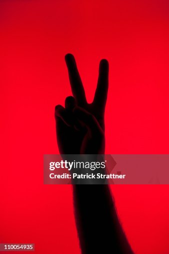 A silhouetted hand making a peace sign A silhouetted hand making a peace sign