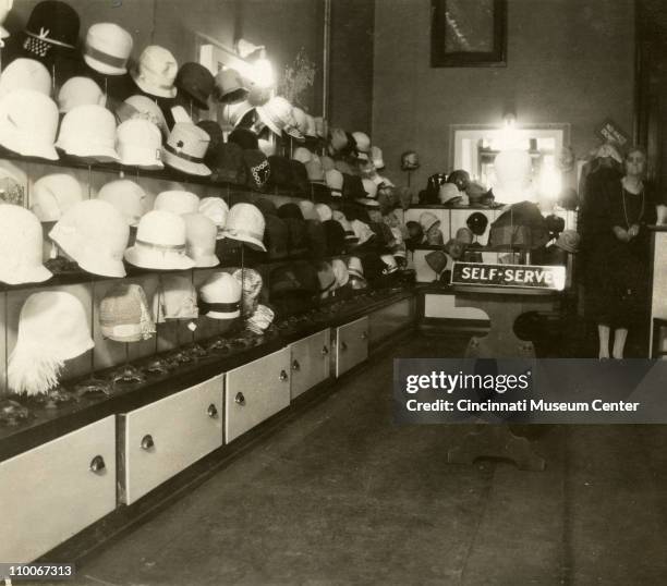 Milliner stands in her hat shop on 6th and Vine streets, Cincinnati, Ohio, 1928.