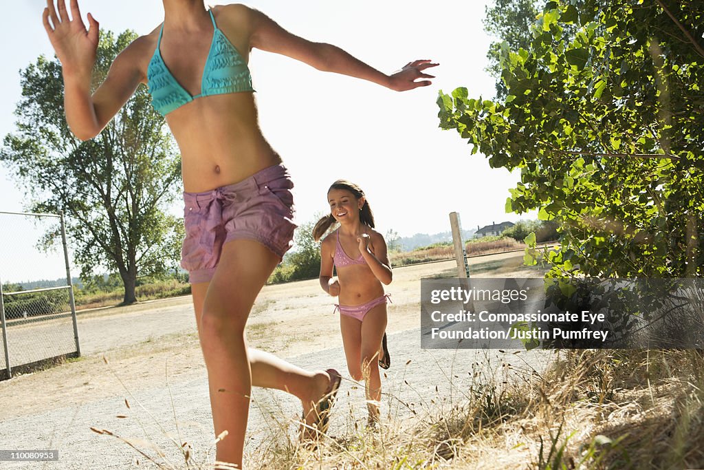 Two smiling girls running in bathing suits