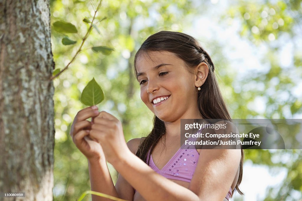 Smiling girl in bathing suit holding a leaf