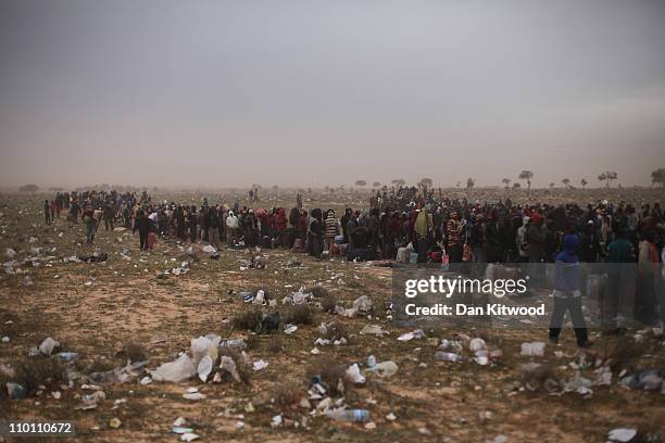 Men from Ghana queue for a coach during a huge sandstorm at a United Nations displacement camp on March 15, 2011 in Ras Jdir, Tunisia. As fighting...