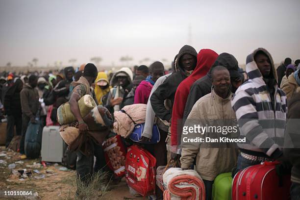 Men from Ghana queue for a coach during a huge sandstorm at a United Nations displacement camp on March 15, 2011 in Ras Jdir, Tunisia. As fighting...