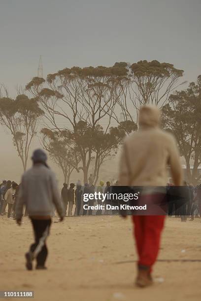 Men queue for food during a sandstorm at a United Nations displacement camp on March 15, 2011 in Ras Jdir, Tunisia. As fighting continues in and...