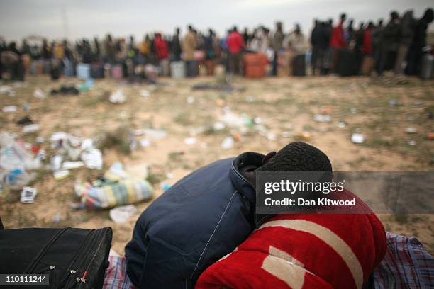 Men from Ghana queue for a coach during a huge sandstorm at a United Nations displacement camp on March 15, 2011 in Ras Jdir, Tunisia. As fighting...