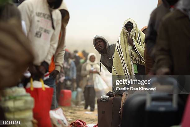 Men from Ghana queue for a coach during a huge sandstorm at a United Nations displacement camp on March 15, 2011 in Ras Jdir, Tunisia. As fighting...