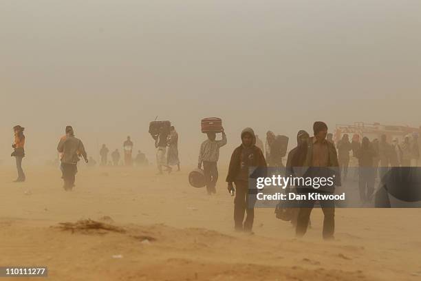 Men walk through a United Nations displacement camp during a sandstorm on March 15, 2011 in Ras Jdir, Tunisia. As fighting continues in and around...