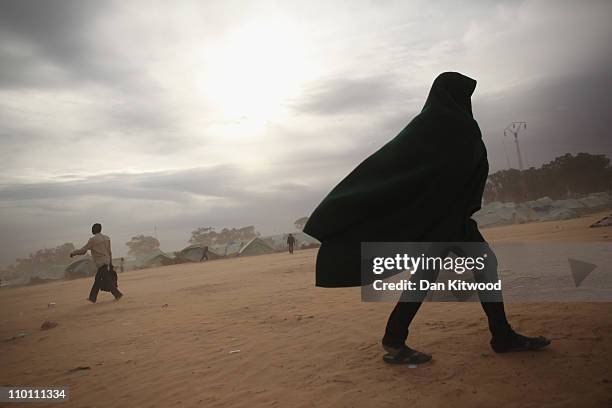 Man walks through a United Nations displacement camp during a sandstorm on March 15, 2011 in Ras Jdir, Tunisia. As fighting continues in and around...