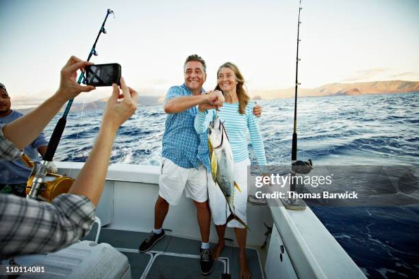couple posing for picture holding fish on boat - hawaii fishing boat stock pictures, royalty-free photos & images