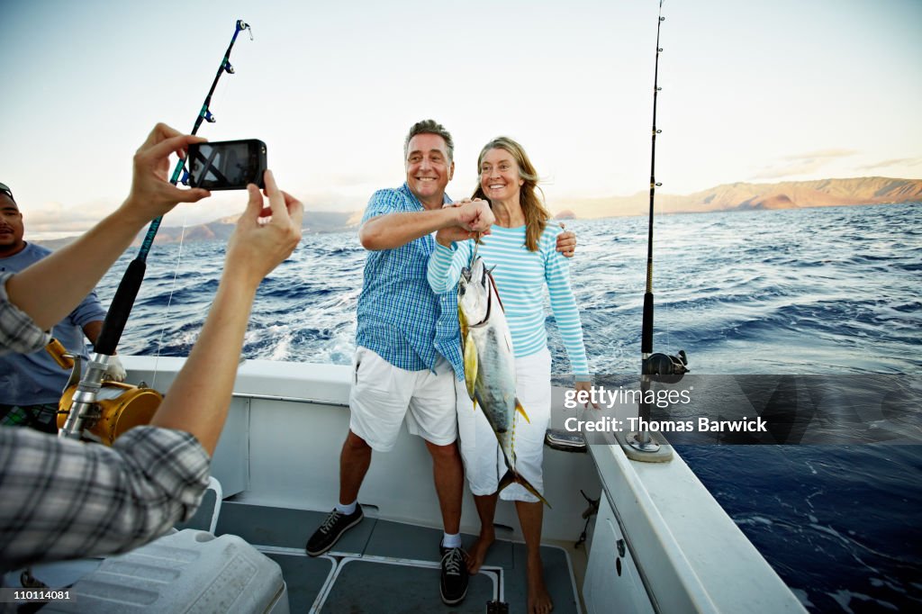 Couple posing for picture holding fish on boat
