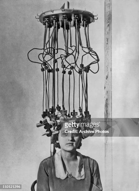 Model having her hair permed by a permanent wave machine at the Hairdressing Fair, White City, London, 25th October 1928.