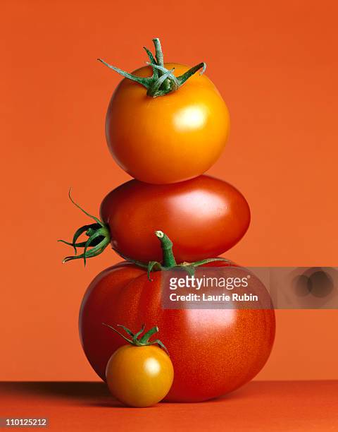 stacked red tomatoes on a red background - tomates stock-fotos und bilder