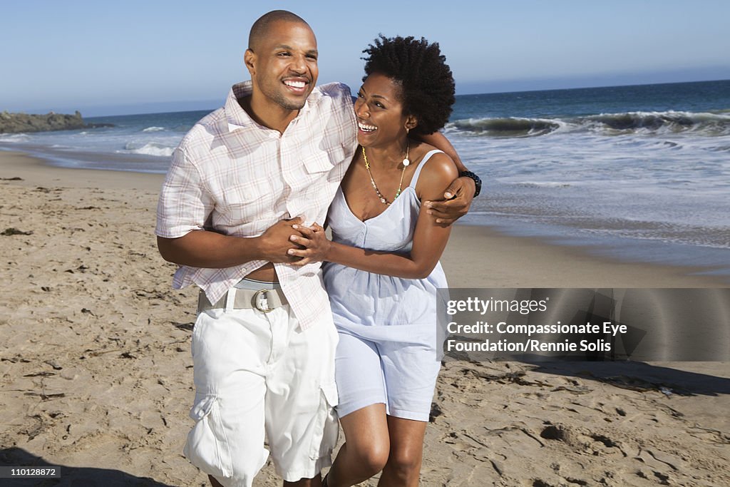 Smiling couple walking down the beach together
