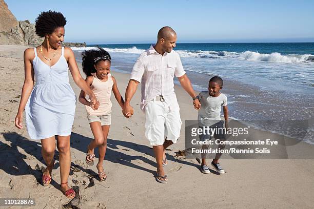 family walking down beach hand in hand - four people holding hands stock pictures, royalty-free photos & images