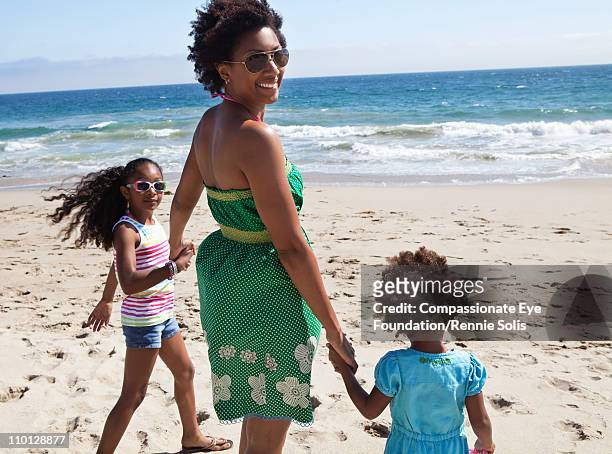 woman and two girls holding hands on the beach - us girls on the beach stock-fotos und bilder