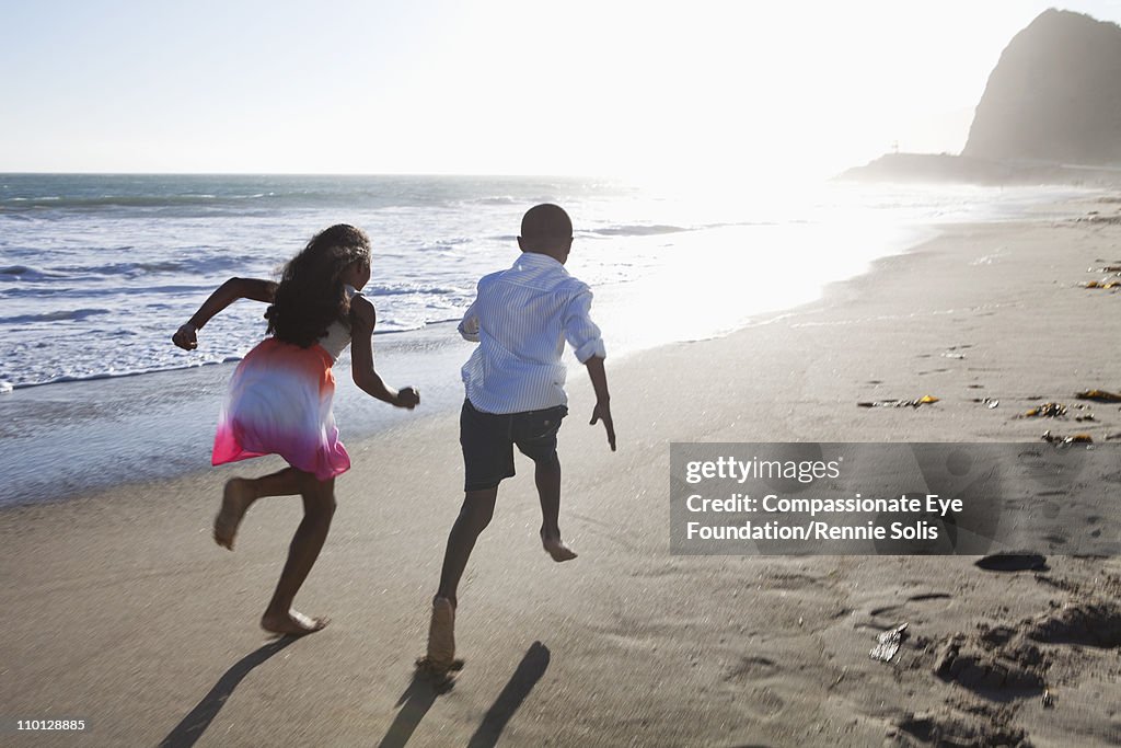 Young girl and boy running down the beach