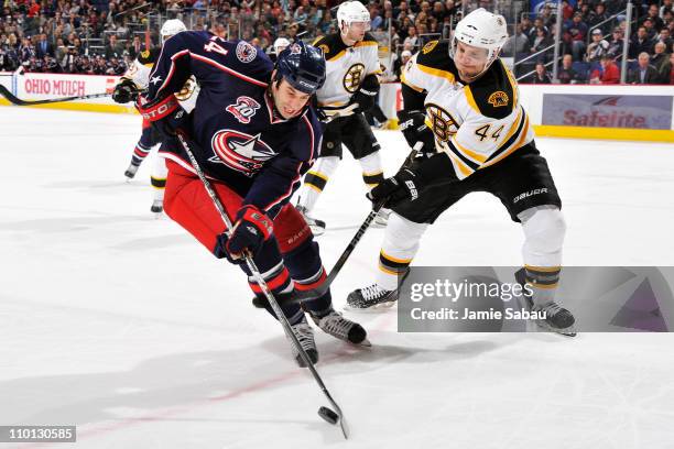 Derek MacKenzie of the Columbus Blue Jackets and Dennis Seidenberg of the Boston Bruins battle for a control of the puck during the first period on...