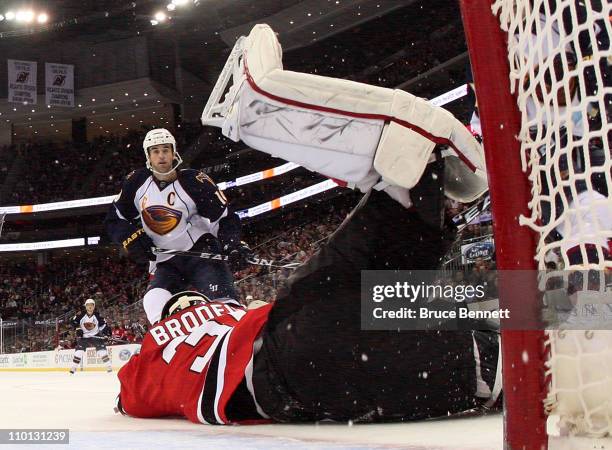 Martin Brodeur of the New Jersey Devils hangs on to the puck as Andrew Ladd of the Atlanta Thrashers looks for a rebound at the Prudential Center on...