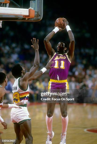 Bob McAdoo of the Los Angeles Lakers shoots over T.R. Dunn of the Denver Nuggets during an NBA basketball game circa 1983 at the McNichols Sports...