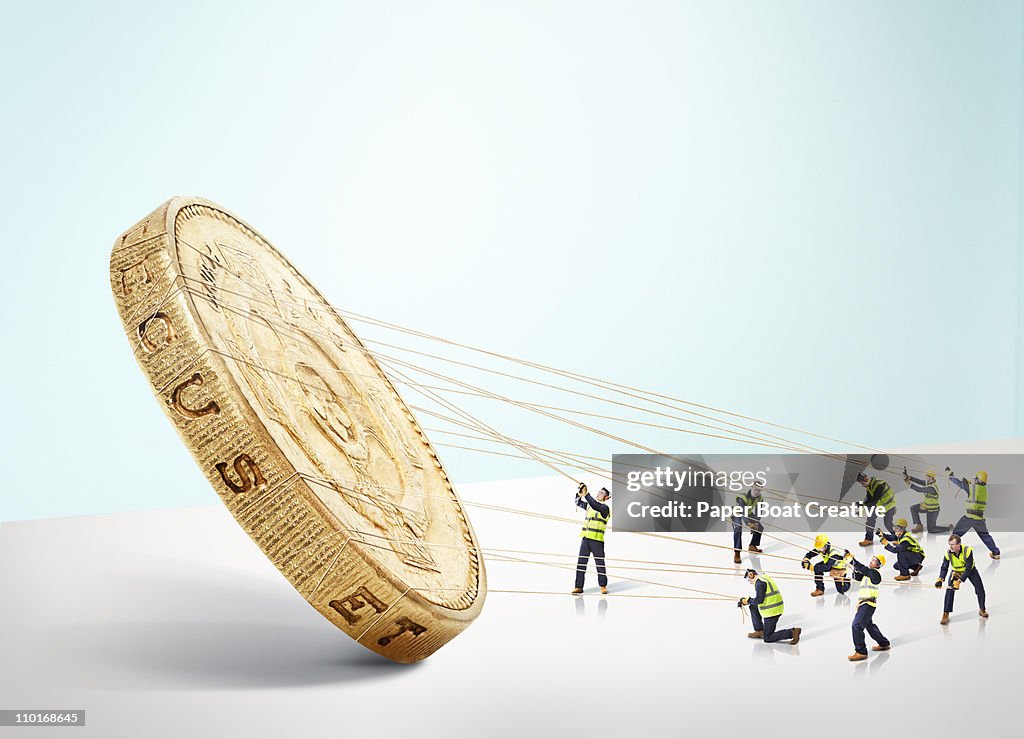 Group of builders carrying a large gold Pound coin