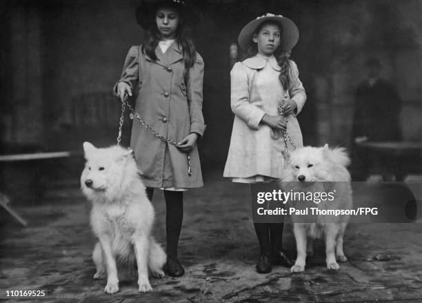 Two young girls with a pair of samoyede's at a Kennel Club Dog Show held at Crystal Palace in London, England circa 1910.