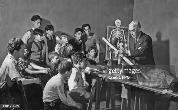 Group of boys being given a practical first aid lesson at school by a doctor circa 1940's.
