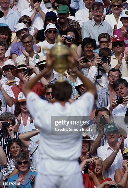 Michael Stich of Germany holds aloft the trophy in triumph to the applauding spectators after defeating Boris Becker during their Men's Singles final...