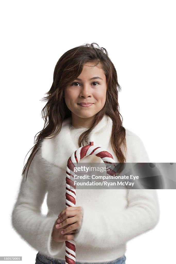 Brunette girl in white holding a candy cane