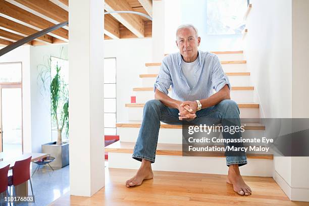 mature man sitting barefoot on indoor stairway - old rich man stock pictures, royalty-free photos & images