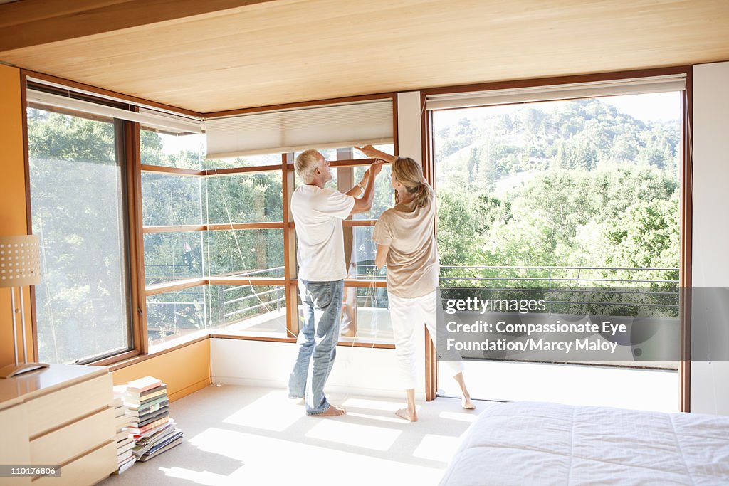 Couple working together to use window blinds