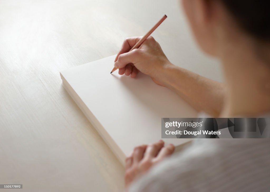 Woman about to draw on blank pad of paper