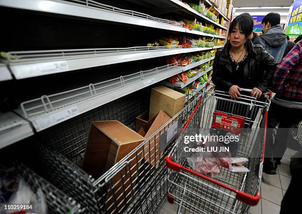 Shoppers look at empty shelves at a supermarket after salt sold out in Beijing on March 17, 2011. Chinese retailers on March 17 reported panic buying...